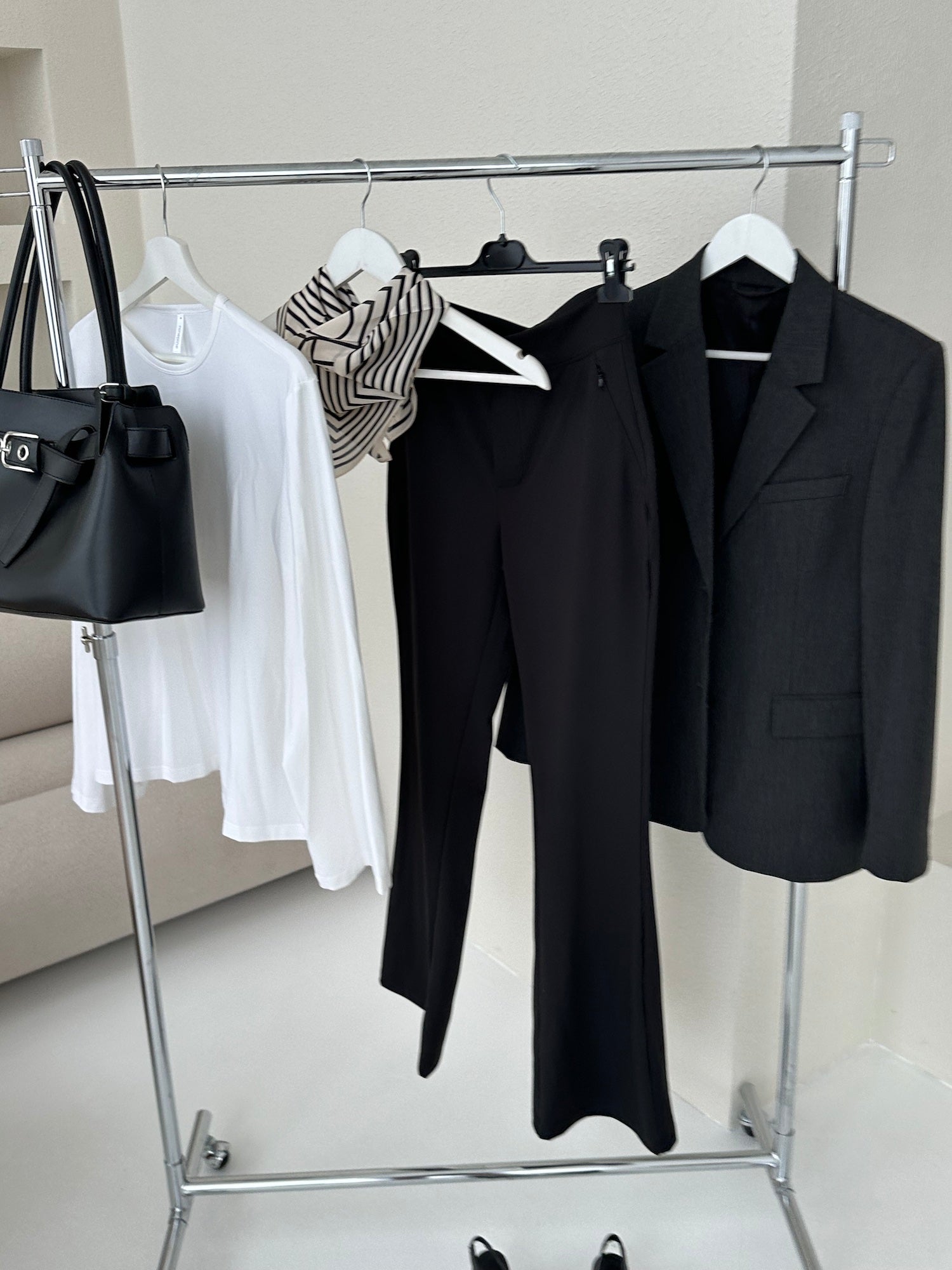 Ninepine capsule wardrobe with white Pima long sleeve top, black Asana pants and structured black blazer, styled with leather bag and scarf in a minimalist outfit.