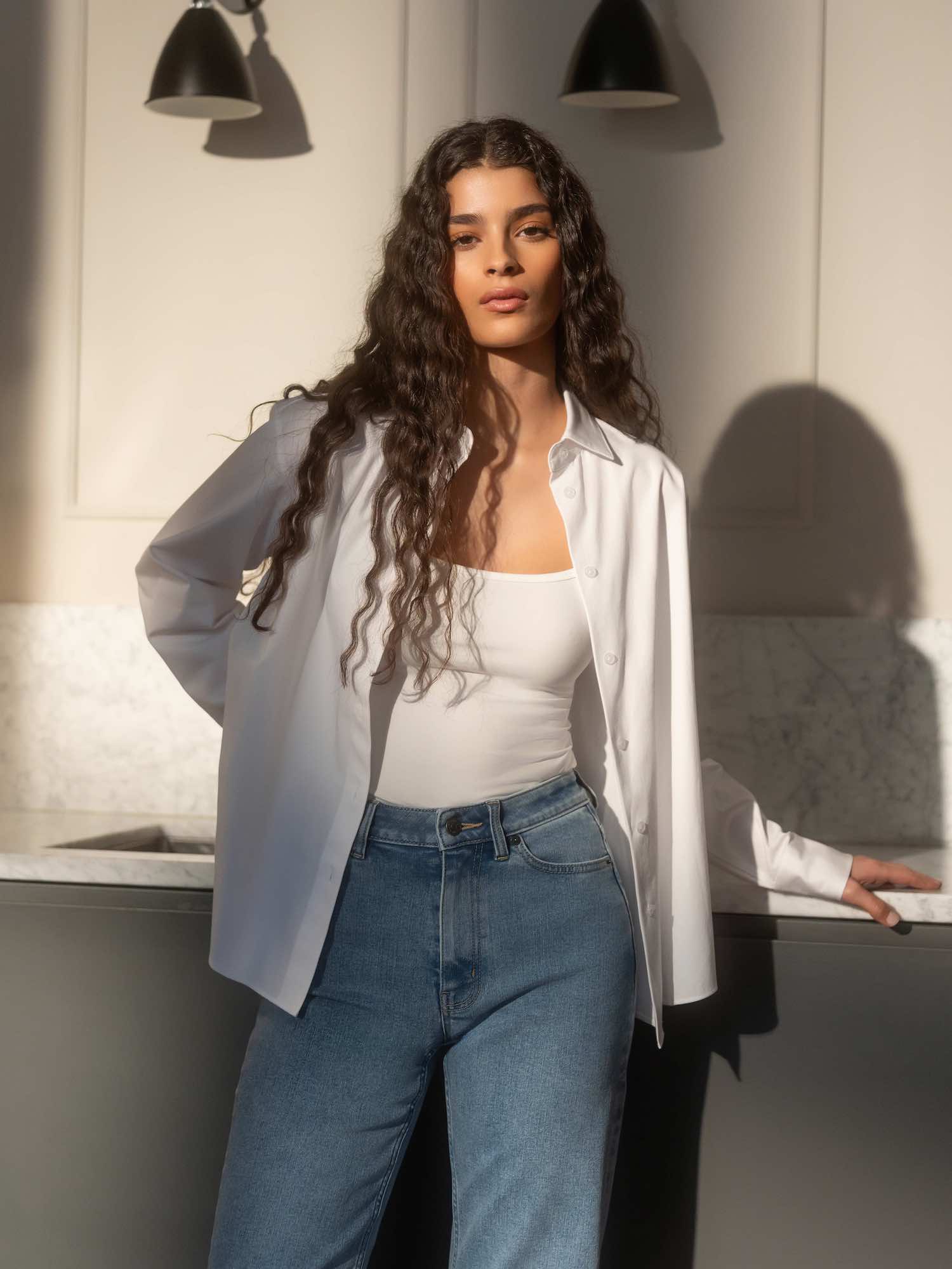 Woman wearing Ninepine ComfortDenim jeans in light blue, styled with white button-up shirt and fitted camisole for a clean everyday outfit.