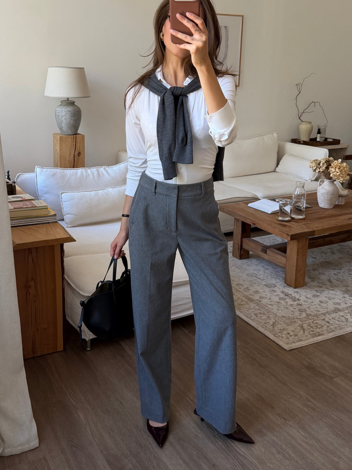 Woman wearing Ninepine Flannel Daily Pant in light grey with a white shirt and boots, standing in front of a mirror.